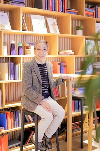 本棚の前に腰かける村田喜代子さん